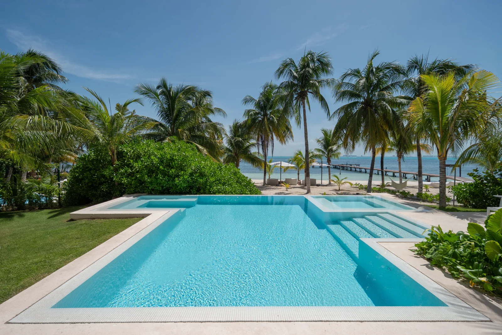 The L-shaped heated pool at Casa Coral running out to the palms and the beach