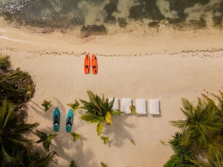 Kayaks, paddleboards and beach towels laid out on the sand, seen from above