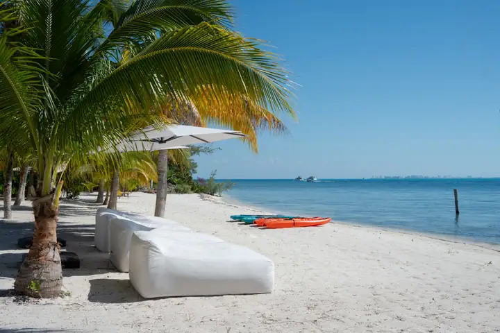 Beach daybeds under the palms on the sand in front of Casa Azul