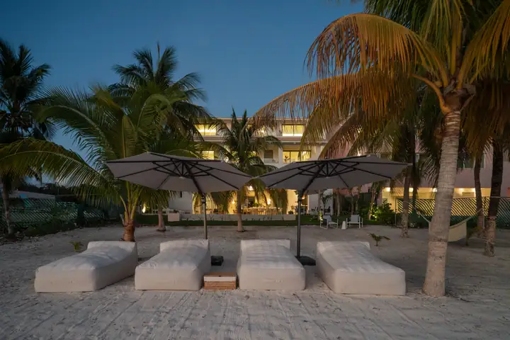 Casa Azul lit at dusk, seen from the beach daybeds on Isla Mujeres