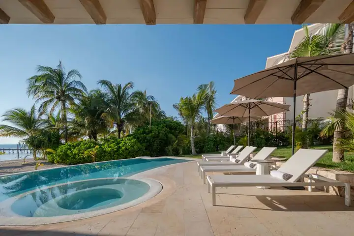 The curved heated pool and loungers at Casa Ceiba, the sea behind the palms