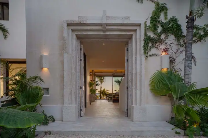 The carved stone entrance portal of Casa Ceiba, framed by tropical planting