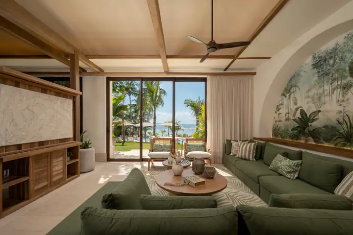 The living room at Casa Ceiba with its palm-jungle mural and green sofas