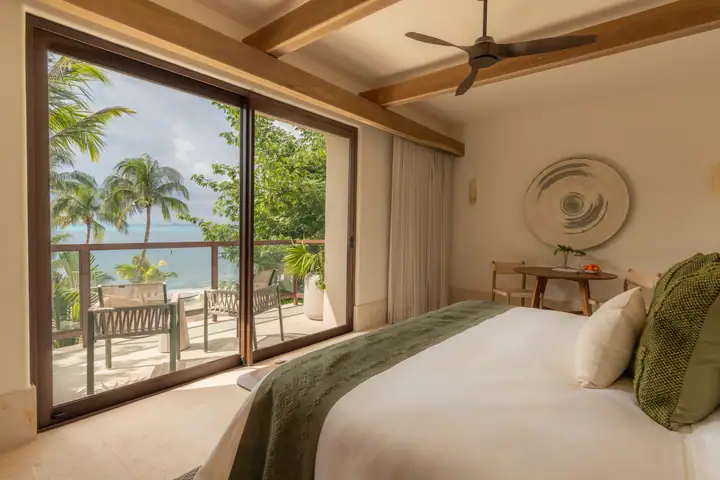 A Casa Ceiba suite looking out through glass to the balcony and the sea