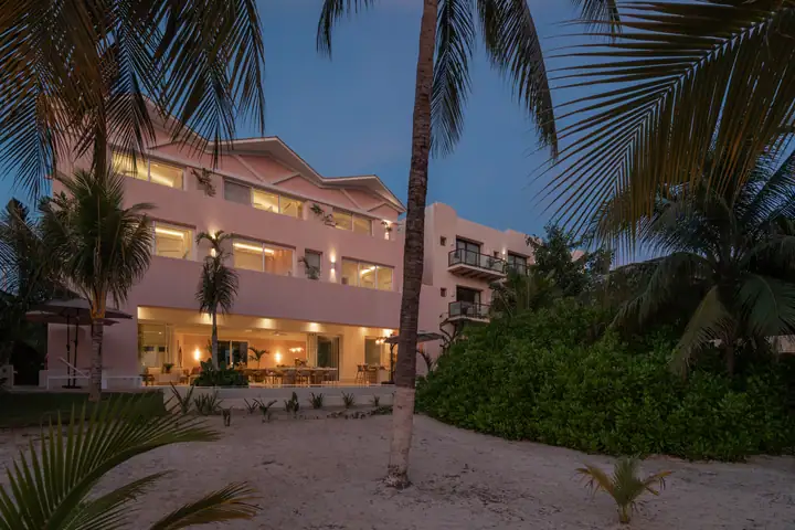 Casa Coral lit at dusk, seen from the beach garden