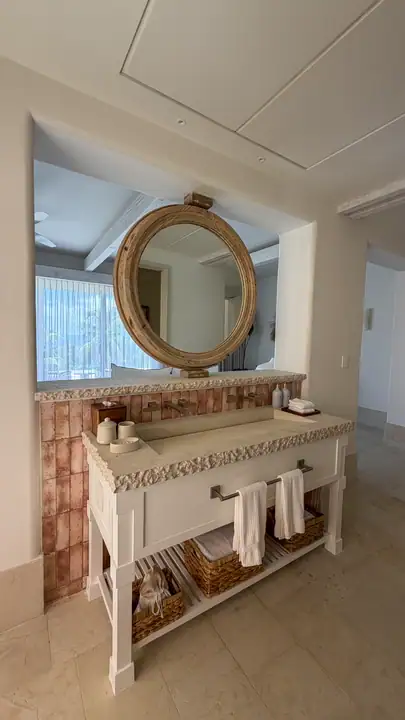 A Casa Coral bathroom with a round mirror and tiled vanity