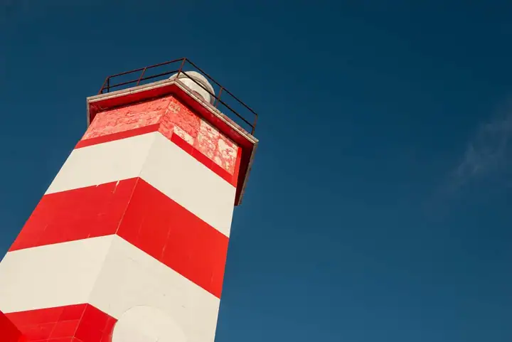 The red-and-white lighthouse on Isla Mujeres against a deep blue sky