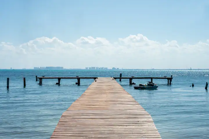 The private wooden dock at La Colección on Isla Mujeres, with the Cancún skyline across the bay